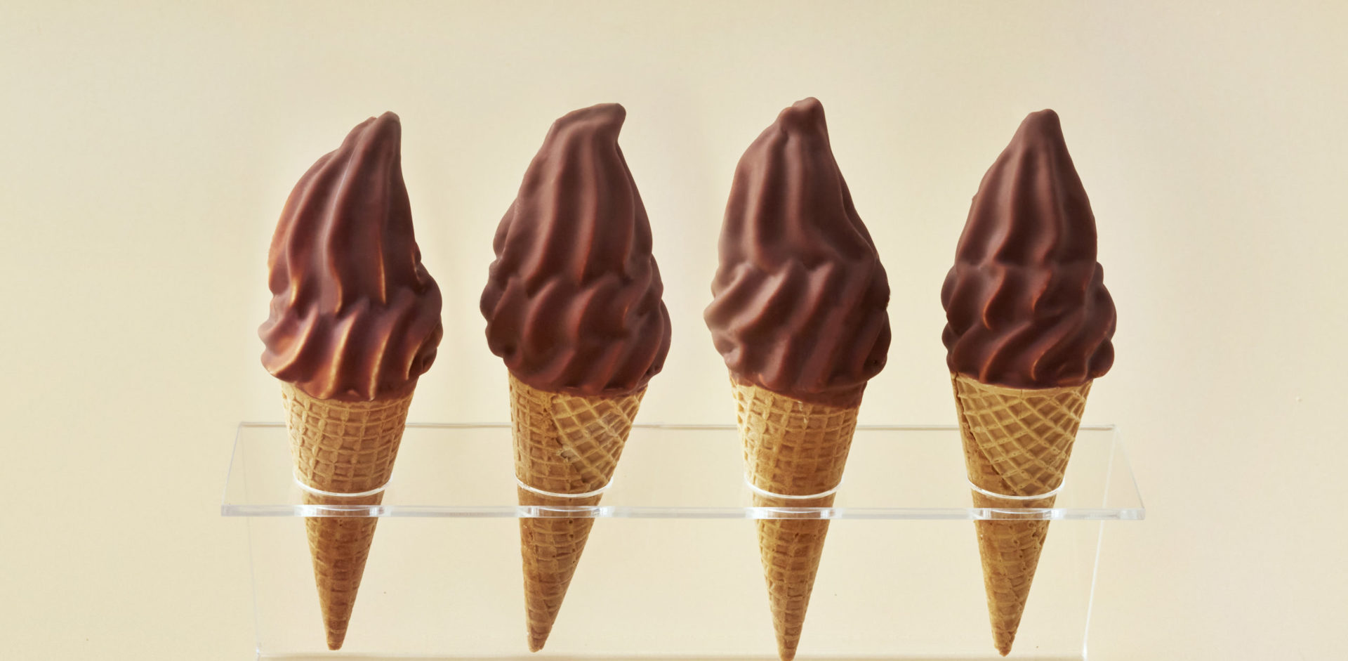 Four chocolate soft-serve ice cream cones.