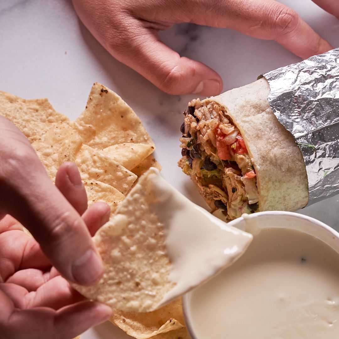 Burrito with tortilla chips and dipping sauce.