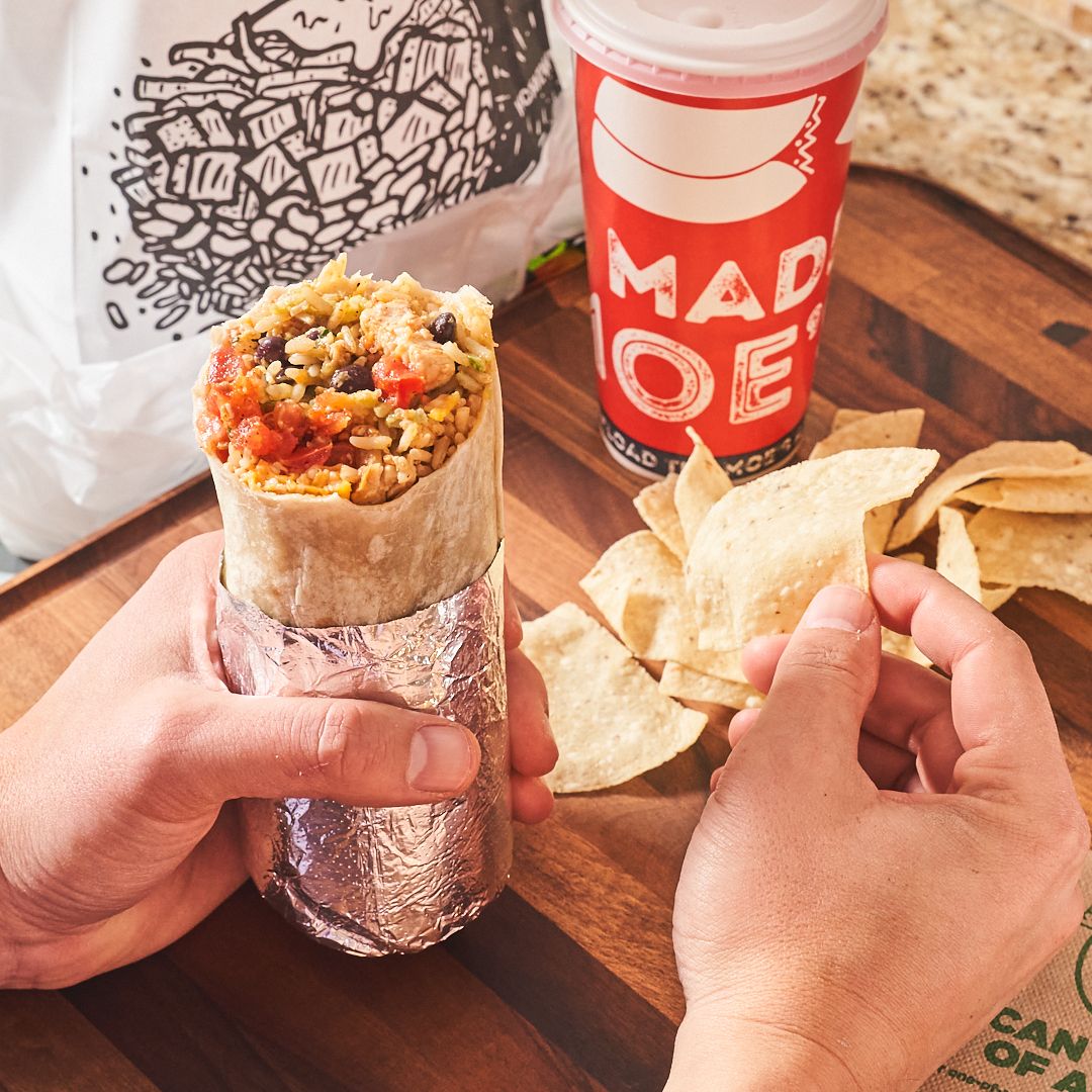 Person holding a burrito and tortilla chips from Moe's.